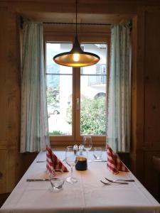 迈恩费尔德Hotel Alpenrose的一张桌子,上面放有酒杯和安乐灯,还有一个窗口