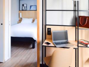 巴黎宜必思巴黎埃菲尔铁塔酒店的一间卧室配有一张床和一张桌子上的笔记本电脑