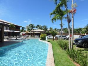 伊塔齐米林Itacimirim - Village na Praia da Espera的棕榈树和汽车度假村的游泳池