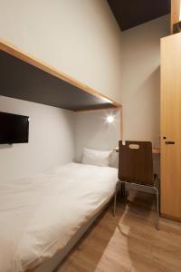 大阪hotel atarayo osaka的一间小卧室,配有一张床和一把椅子