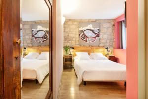 圣塞瓦斯蒂安Hotel Okako San Sebastian的一间卧室配有两张床和镜子
