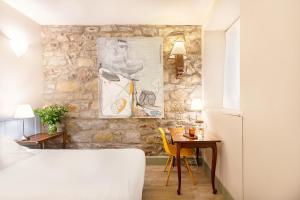 圣塞瓦斯蒂安Hotel Okako San Sebastian的一间卧室设有石墙、一张桌子和一张床