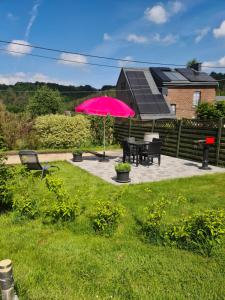 斯帕Ké dodo sous le château !!!的一个带粉红色遮阳伞和桌椅的庭院