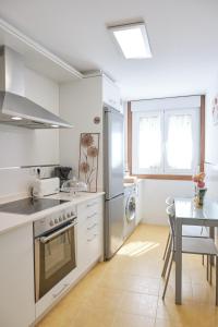 欧德鲁佐Peregrina Pension 3的白色的厨房配有桌子和炉灶。 顶部烤箱