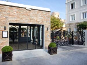 马赛Mercure Marseille Centre Bompard La Corniche的砖砌的建筑,有玻璃门和两株植物