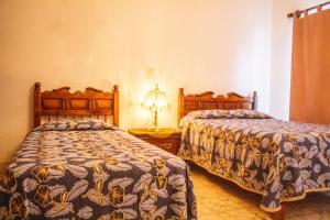 马斯科塔Villa Flores, casa en el centro de Mascota的一间卧室设有两张床和一张桌子上的台灯。