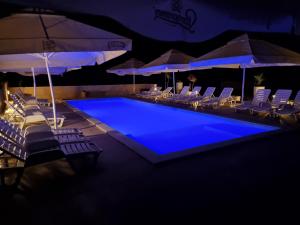 希洛Pension Riviera-Šilo的游泳池在晚上提供椅子和遮阳伞