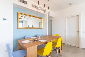 纳哈里亚Stunning 4-bedroom Apartment Next to Achziv Beach by Sea N' Rent的一间带木桌和黄色椅子的用餐室