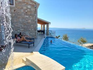 奥瑞比克Lavanda Mobile Homes & Villas的两人坐在海边的游泳池里