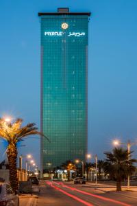 利雅德Myrtle Hotel - Al Sahafa的一座高大的绿色建筑,上面有时钟