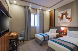 利雅德Myrtle Hotel - Al Sahafa的酒店客房设有两张床和一台平面电视。