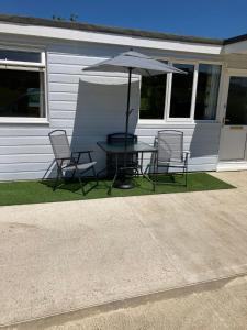 桑当8 Sandy Bottom Sandown Bay Holiday Park, reduced ferry, please contact us的房屋前的桌椅和遮阳伞