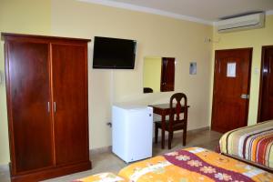 Huaquillas索尔德尔苏尔酒店的一间卧室配有一张床和一张桌子及一台电视