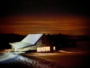 NovoťHacienda na Orave的一座在晚上有雪盖屋顶的建筑