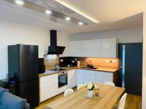 多克西Apartmány DOME的厨房配有木桌和黑冰箱。