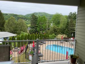 布罗蒙Le Champlain Condo-Hôtel的享有游泳池和山脉美景的阳台。