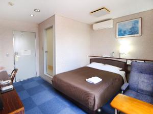 挂川市Royal Inn Kakegawa (Station Hotel 2)的酒店客房配有一张床、一张桌子和一把椅子。