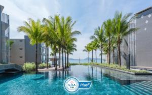 芭东海滩Oceanfront Beach Resort - SHA Extra Plus的一座棕榈树游泳池,位于建筑前
