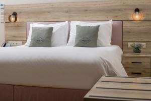 雅典Acropolis Vision的一张带白色枕头和木制床头板的大床