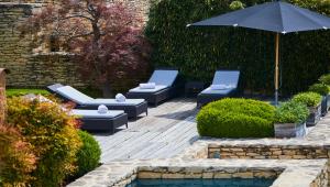 圣萨蒂南艾普特Domaine des Andéols的一个带躺椅和遮阳伞的庭院,毗邻游泳池