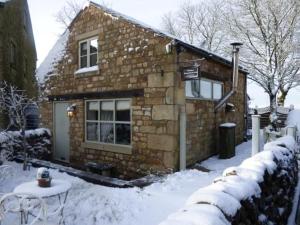斯基普顿Pinfold Holiday Cottage的雪中带桌子的石头房子