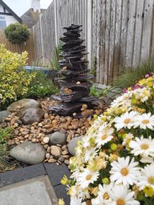 滨海克拉克顿Viva Guest House的花园,花园前方有石头喷泉和鲜花