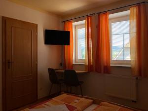 捷克克鲁姆洛夫玛雅特膳食公寓的一间卧室配有一张床、一张书桌和两个窗户。