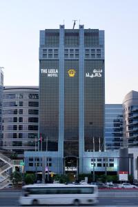 迪拜The Leela Hotel的一辆白色的公共汽车在建筑物前行驶