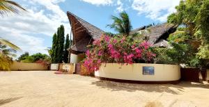 马特姆维Kena Beach Hotel的一座种植了粉红色花的房屋