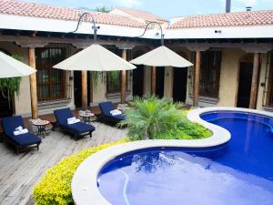 危地马拉安地瓜安提瓜卡米诺雷亚度假酒店的一座带椅子和遮阳伞的游泳池位于一座建筑旁边