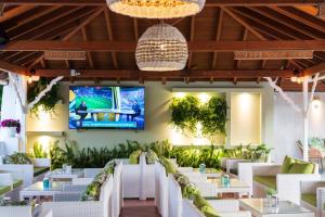 特劳洛斯Almira Hotel的餐厅设有白色桌子和墙上的电视