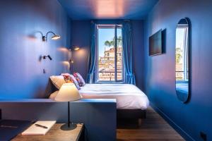 尼斯Boutique Hotel Nice Côte d'azur的蓝色的卧室设有床和窗户