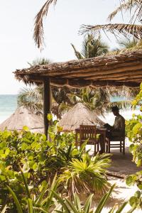 图卢姆图卢姆恩坎塔达酒店的坐在海滩桌子上的男人