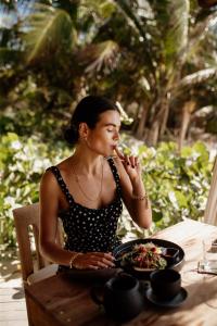图卢姆图卢姆恩坎塔达酒店的坐在餐桌旁吃一碗食物的女人