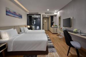 洞海Khách sạn SAM Quảng Bình的酒店客房设有两张床、一张桌子和一台电视。