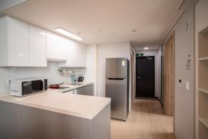 济州市Jeju Central Park Residence的厨房配有白色橱柜和不锈钢冰箱