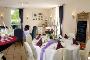 希尔德斯海姆海德乡间别墅酒店的一间用餐室,配有白色的桌椅和紫色的弓