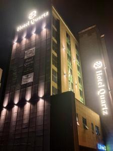 釜山Hotel Quatz的夜间标有标志的酒店大楼