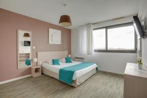 敦刻尔克All Suites Appart Hôtel Dunkerque的一间卧室配有一张带蓝色枕头的床和一扇窗户。