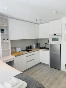 直布罗陀CP Top floor luxury studio的厨房配有白色橱柜和不锈钢用具