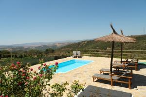 卡萨雷斯The Wild Olive Andalucía Agave Guestroom的一个带稻草伞和两把椅子及长凳的游泳池