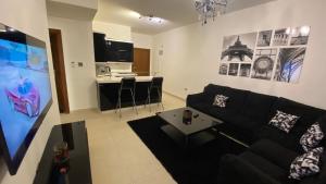安曼Dair Ghbar Apartment的一间带黑色沙发的客厅和一间厨房