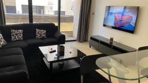 安曼Dair Ghbar Apartment的客厅配有黑色沙发和电视