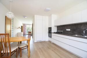 奥洛穆茨Sunny apartment的厨房配有白色橱柜和木桌