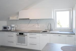 拉布Apartmani Vrtodusic的白色的厨房设有水槽和窗户