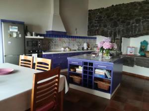 GuarazocaCasa Rural Los Mozos的厨房配有蓝色橱柜和桌椅