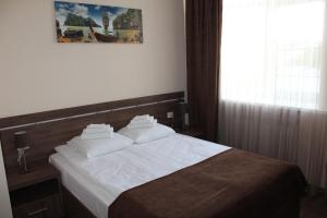 卡卢加Гостиница ОКА的一间卧室配有一张带白色床单的床和一扇窗户。
