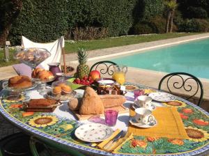 马尔米堡Relais di Alice- Adults Only的桌边的桌边,桌边有面包和水果,早餐在泳池边