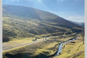 WanlockheadGlendyne Cottages, Highest Village in Scotland的骑着自行车在山坡上行驶的人