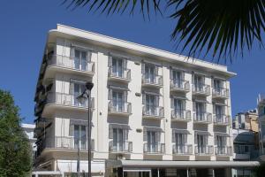 卡托利卡Hotel Gambrinus Mare的带阳台的白色建筑和棕榈树